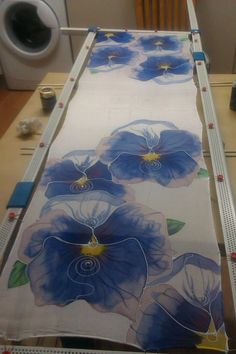 the table is covered with blue flowers on white paper and has an ironing board in front of it