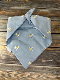 a blue bandana with yellow and white flowers on it sitting on a wooden surface