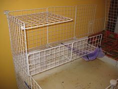 a white cage that has two birds in it and one is on top of the bed