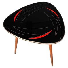 a black and red table sitting on top of a wooden leg rest with two legs