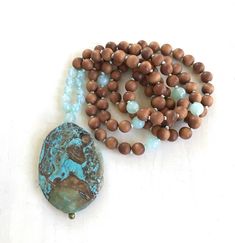 "Tranquility Mala Beads - Ocean Jasper & Sandalwood Beads - Hand Knotted - 108 Bead Mala - Length approx. 40\" The rhythmic cadence of the sea has always called humanity to its shores. This Ocean Jasper and Sandalwood Mala bead necklace from True Nature Jewelry brings that same spirit of peace and letting go. Hand knotted for flexibility and beauty, it features soothing and fragrant Sandalwood beads and Light Aqua Agate to help balance the emotions. A large Ocean Jasper pendant which brings Spiritual Beaded Necklaces With Oval Beads For Beach, Earthy Wooden Beads Jewelry For Meditation, Rustic Round Beads Jewelry For Meditation, Rustic Jewelry With Round Beads For Meditation, Rustic Round Bead Jewelry For Meditation, Nature-inspired Wooden Beads Jewelry For Meditation, Earthy Healing Beads, Turquoise Spiritual Beads For Meditation, Spiritual Turquoise Beads For Meditation