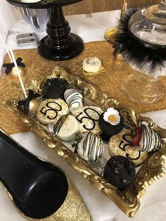 an elaborately decorated table with gold and black desserts on it's tray