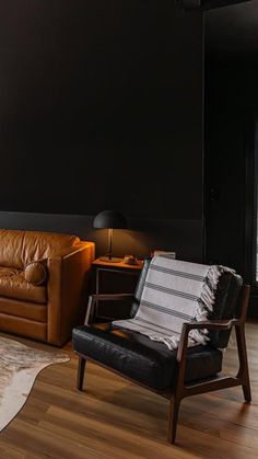 a living room with black walls and leather furniture