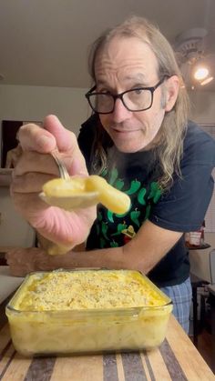 a man holding a spoon over a casserole dish