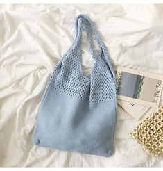 a blue bag sitting on top of a white bed next to a purse and wallet