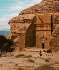 a man leading a horse in front of an ancient building that is carved into the side of a mountain