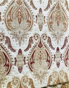 an old wallpaper with red and gold designs on white fabric, including paisleys