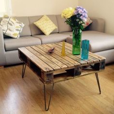 a wooden table sitting on top of a hard wood floor next to a gray couch