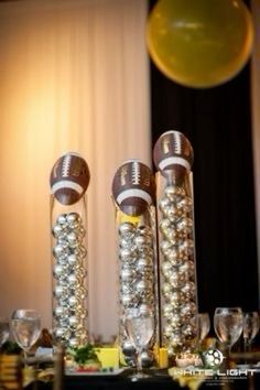 two footballs are sitting on top of each other in front of wine glasses and champagne flutes