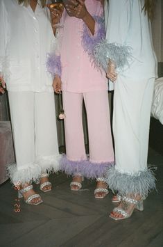 three women in white and pink outfits standing next to each other with their cell phones