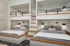 two beds in a room with white walls and wooden steps leading up to the second floor