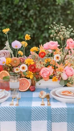 the table is set with flowers, fruit and other things to eat for dinner or brunch