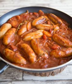 sausages and tomato sauce in a pan on a wooden table