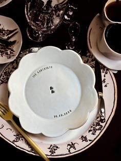 a white plate topped with a black and white design next to two silverware on top of a table