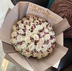 a bouquet of white roses is wrapped in brown paper and says, will you be my girlfriend?