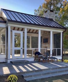 a person laying on the ground in front of a house with glass doors and windows