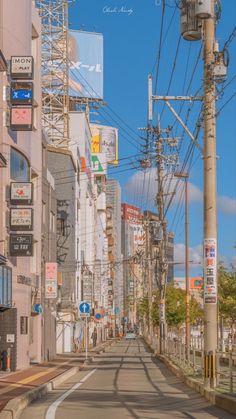 an empty city street with lots of power lines above the buildings and people walking on the sidewalk