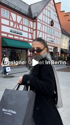 a woman is walking down the street with shopping bags in her hand and wearing sunglasses