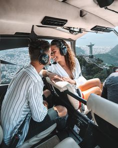 two people sitting in the cockpit of an airplane with headphones on, looking at each other