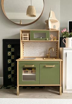 a kitchen with green cabinets and a round mirror