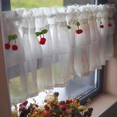 the curtains are hanging on the window sill with cherries and flowers in them