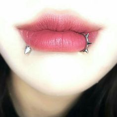 a woman's lips are adorned with silver spiked studs and pink lipstick