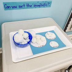 a bowl of cotton balls sitting on top of a white tray next to a blue sign