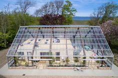 an aerial view of a glass house in the middle of a park with lots of trees