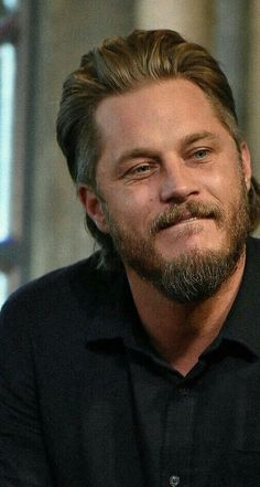 a close up of a person wearing a black shirt with a beard and long hair