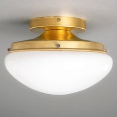 a close up of a light fixture with a white glass ball on the bottom and gold trim