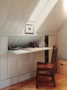 a chair sitting on top of a hard wood floor under a slanted ceiling next to a desk