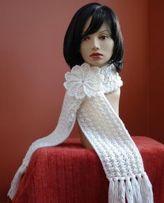 a mannequin wearing a white scarf on top of a red blanketed surface