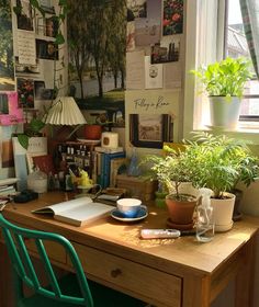 a wooden desk topped with lots of books and plants next to a window covered in posters