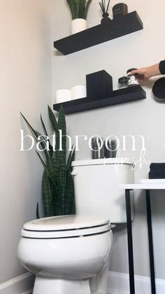 a person is cleaning the toilet in a bathroom with plants on the shelves above it