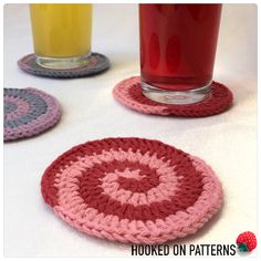 three crocheted coasters on a table next to a glass of orange juice