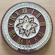 a decorative clock with roman numerals on the face and numbers in gold, white, and maroon