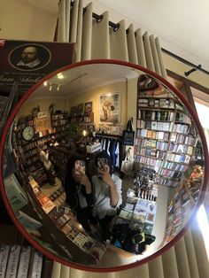 a woman taking a selfie in front of a mirror with books on the shelves