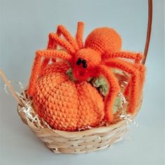 an orange crocheted spider sitting on top of a pumpkin in a wicker basket