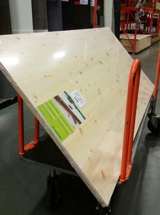 there is a table that has been made out of plywood and orange metal bars