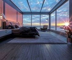 a bedroom with large windows overlooking the ocean at sunset or sunrise, is pictured here