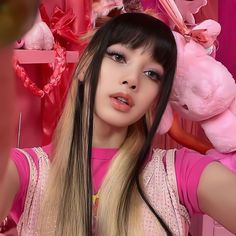 a woman with long hair and pink shirt holding a teddy bear in front of her face