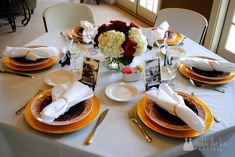 the table is set with plates, silverware and flowers in vases on them