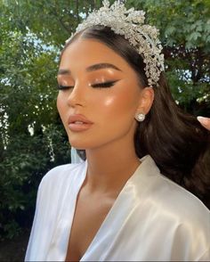 a woman wearing a tiara and holding her hair in one hand while looking at the camera