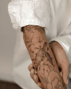 a person with a tattoo on their arm holding something in his hand and wearing a white shirt