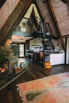 a spiral staircase in the middle of a living room with wood floors and exposed ceilings