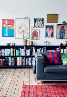 a living room filled with lots of books and pictures on the wall next to a couch