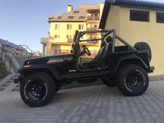 a black jeep parked in front of a yellow building