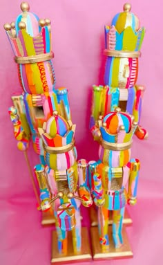 two brightly colored carnival rides on wooden stands against a pink background with gold trimmings