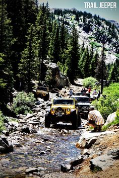 two jeeps driving through a stream in the mountains