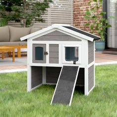 a dog house that is in the grass with a ramp leading up to it's door